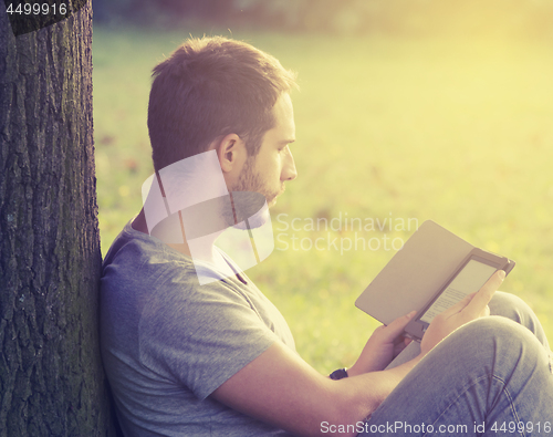 Image of Young man reading e-book