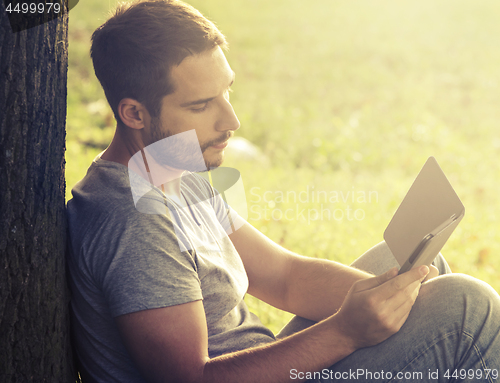 Image of Young man reading e-book