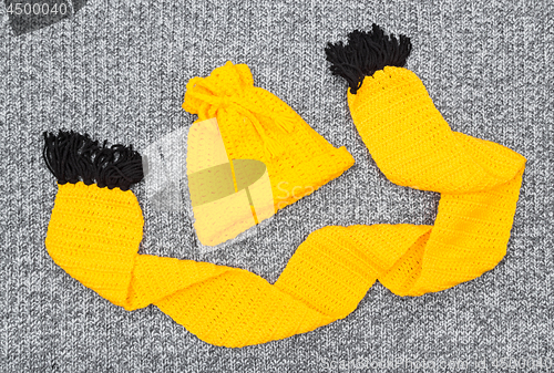 Image of Yellow knitted hat and scarf on gray wool background