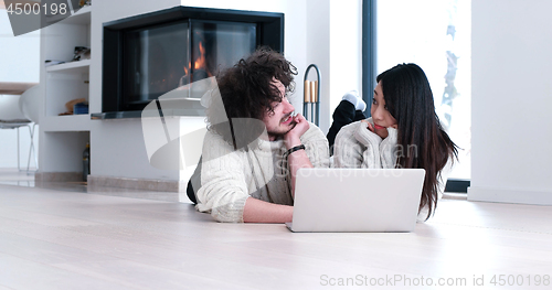 Image of young multiethnic couple using a laptop on the floor