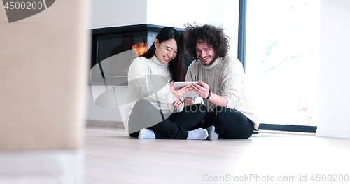 Image of Young Couple using digital tablet on the floor