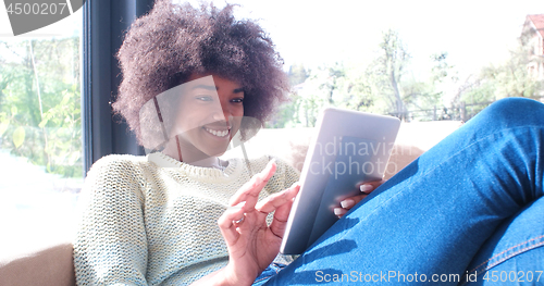 Image of african american woman at home using digital tablet