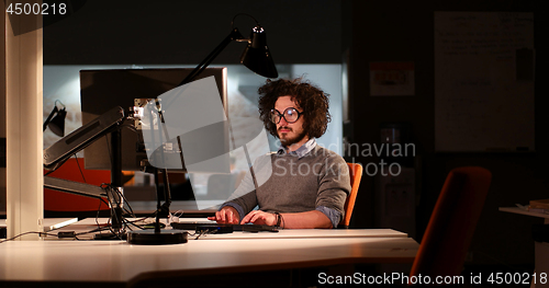 Image of man working on computer in dark office