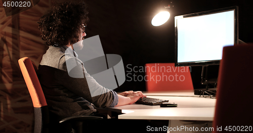 Image of man working on computer in dark office