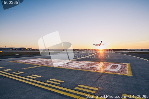 Image of Airplane landing at sunset