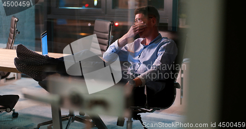 Image of businessman sitting with legs on desk at office