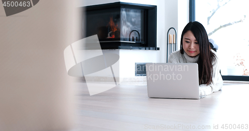 Image of Asian woman using laptop on floor