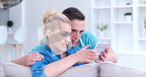 Image of couple relaxing at  home with tablet computers