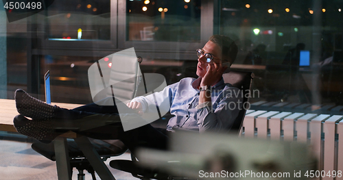 Image of businessman sitting with legs on desk at office