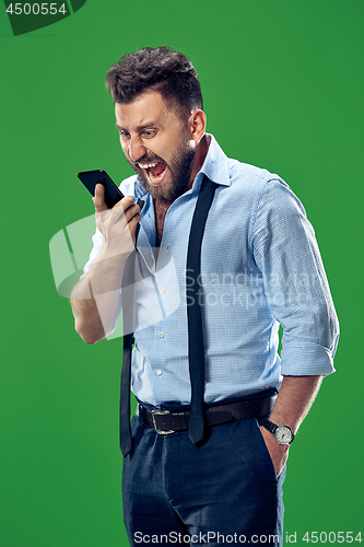 Image of The young emotional angry man screaming on green studio background