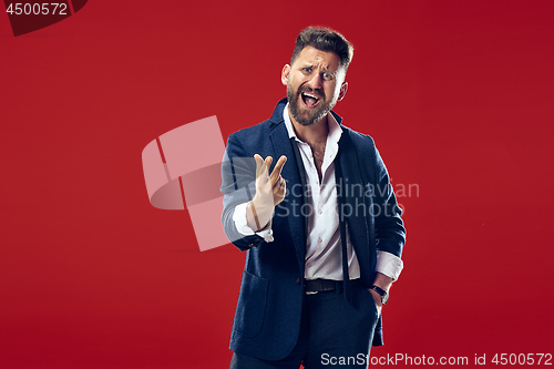 Image of Beautiful male half-length portrait isolated on red studio backgroud. The young emotional surprised man