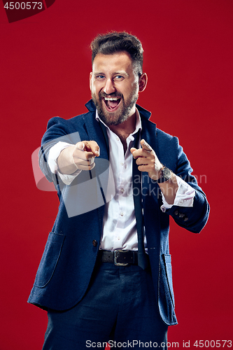 Image of The happy business man point you and want you, half length closeup portrait on red background.