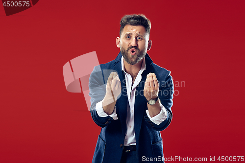 Image of Beautiful male half-length portrait isolated on red studio backgroud. The young emotional surprised man