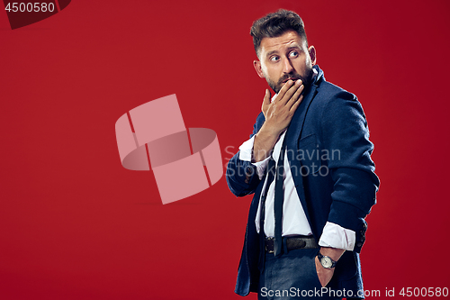 Image of The young man whispering a secret behind her hand over red background