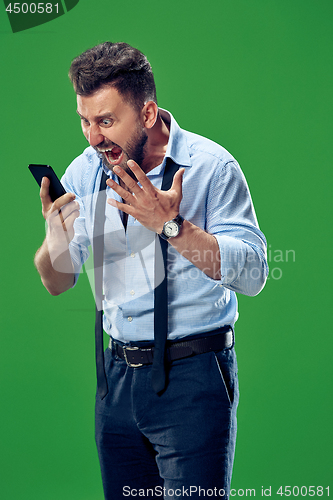 Image of The young emotional angry man screaming on green studio background