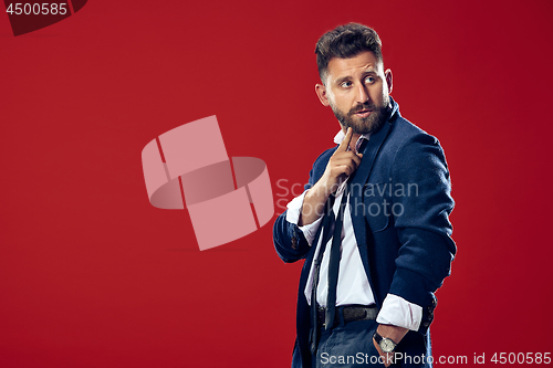 Image of The young man whispering a secret behind her hand over red background