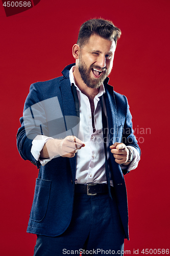 Image of The happy business man point you and want you, half length closeup portrait on red background.