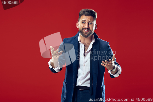 Image of Beautiful male half-length portrait isolated on red studio backgroud. The young emotional surprised man