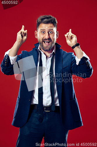 Image of The young attractive man looking suprised isolated on red