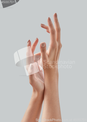 Image of Beautiful woman hands with pastel manicured nails isolated on a gray background, copy space. Massage of hands using cream. Close up.