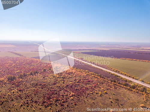 Image of Panoramic landscape with endless farmlands, forests and highway in a autumn time on a background of clear sky. Aerial view from drone.