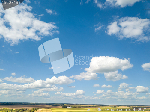 Image of Cloudy aerial landscape with white clouds and fields on a blue sky background. Aerial view from drone.