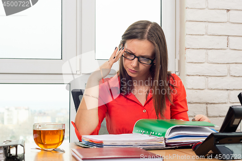 Image of An office employee carefully and thoughtfully reads the documents in the folder