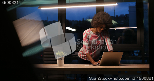 Image of black businesswoman using a laptop in night startup office