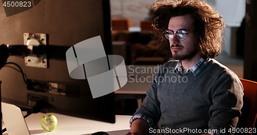 Image of man working on computer in dark office