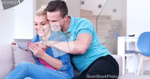 Image of couple relaxing at  home with tablet computers