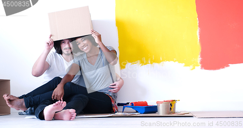 Image of young multiethnic couple playing with cardboard boxes