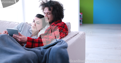 Image of couple relaxing at  home with tablet computers