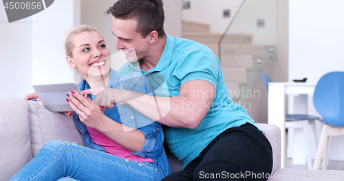 Image of couple relaxing at  home with tablet computers