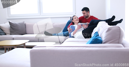 Image of couple relaxing at  home with tablet computers