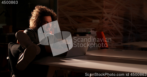 Image of businessman sitting with legs on desk at office