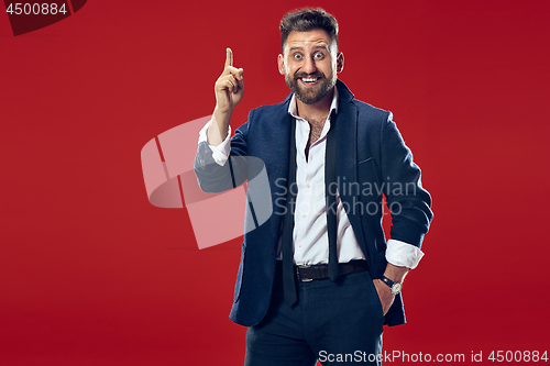 Image of The young attractive man looking suprised isolated on red
