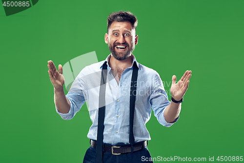 Image of The young attractive man looking suprised isolated on green
