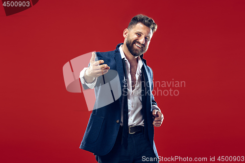 Image of The happy business man standing and smiling against red background.