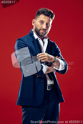 Image of Male beauty concept. Portrait of a fashionable young man with stylish haircut wearing trendy suit posing over red background.