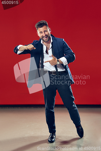 Image of The happy business man pointing to left, half length closeup portrait on red background.