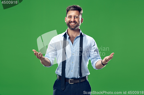 Image of The young attractive man looking suprised isolated on green