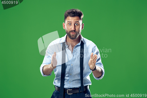 Image of The young attractive man looking suprised isolated on green