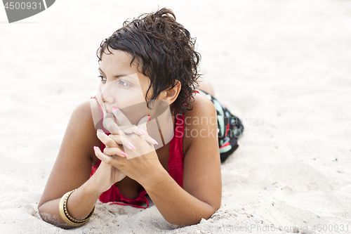 Image of Attractive brunet woman in red lying on a sand.