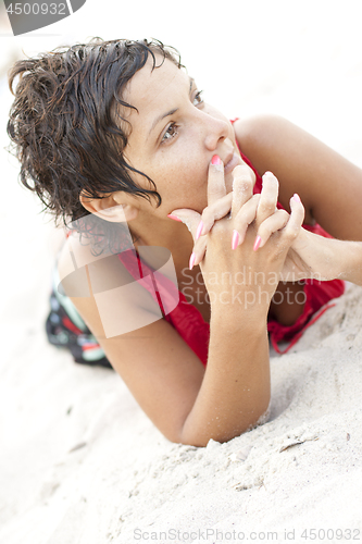 Image of Attractive brunet woman in red lying on a sand.