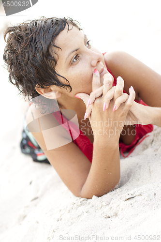 Image of Attractive brunet woman in red lying on a sand.