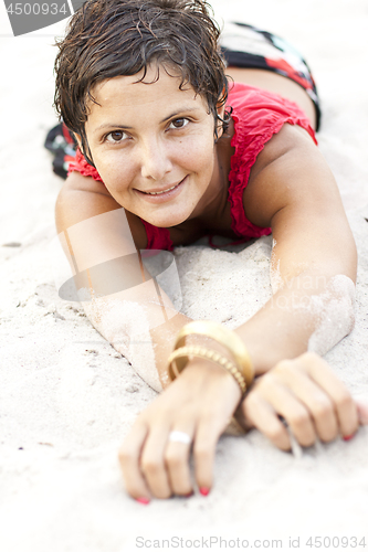 Image of Attractive brunet woman in red lying on a sand.