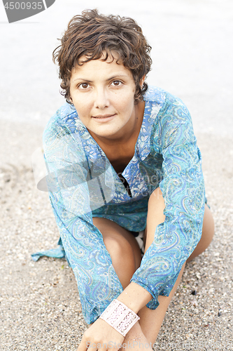 Image of Brunet woman in blue dress on the beach.