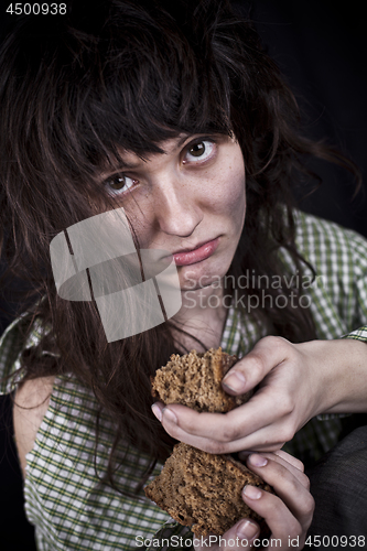 Image of Poor beggar woman with a piece of bread.