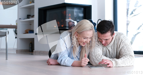 Image of Young Couple using digital tablet on the floor