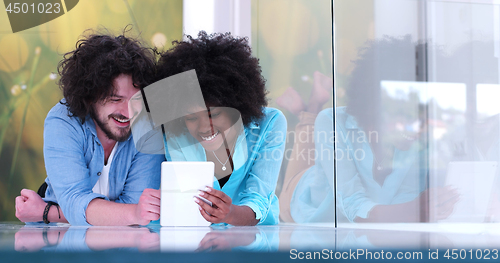 Image of Couple relaxing together at home with tablet computer